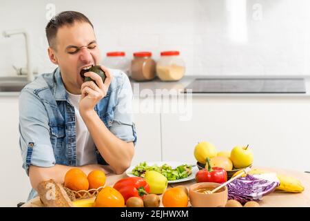 Glücklicher junger Mann Vorbereitung romantisches Abendessen Suche Gemüse Rezepte Diät-Menü, lächelnd Mann Kochen gesunde vegane Lebensmittel geschnitten Salat in der Küche Stockfoto