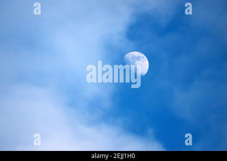 Aufgehender Mond in blauem Himmel mit weißen Wolken Stockfoto