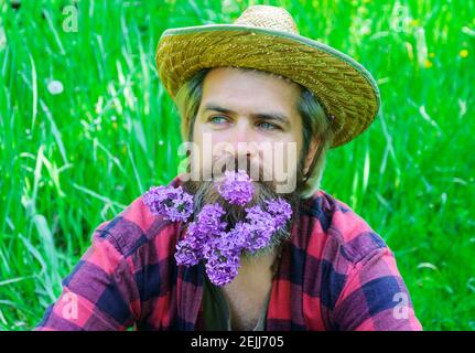 Schöner Frühlingsmann mit Blumenbart. Bärtiger Rüde mit dekoriertem Bart. Stockfoto