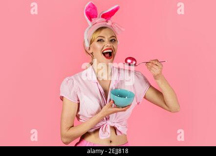 Osterfest. Frau mit gefärbtem Ei. Lächelndes Mädchen in Hasenohren. Eier jagen. Stockfoto