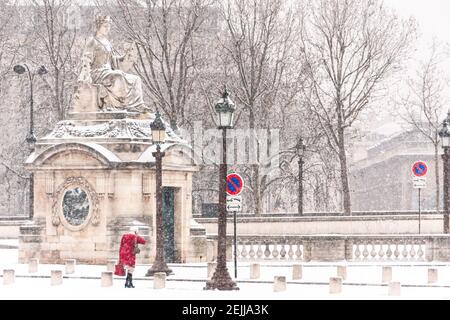 Frau mit einem roten Mantel geht in Place de la Concorde in Paris im Winter beim Schneefall Stockfoto
