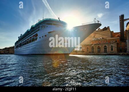 Ozeandampfer im Hafen von altem Valletta. Blick vom Wasserstand auf riesiges, weißes Schiff gegen die Sonne. Malta. Stockfoto