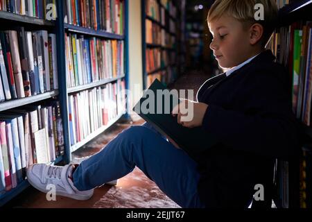 Boy sitzt in einem Buchladen und lesen Buch, Bildung und Schulkonzept. In der Bibliothek Stockfoto