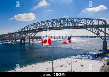 Port Huron, Michigan - die Flaggen der USA und Kanadas fliegen an der Blue Water Bridge, die die Vereinigten Staaten (rechts) und Kanada über die St.. Stockfoto