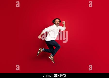 In voller Länge Profil Porträt der fröhlichen Person springen läuft offenen Mund isoliert auf rotem Hintergrund. Stockfoto