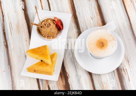 Tasse heißen Cappuccino Kaffee begleitet von einem Stück Kuchen und eine Kugel Zimtschokolade-Eis Stockfoto