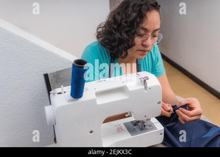 Fröhliche Frau Nähen, während sie an ihrem Arbeitsplatz in sitzen Modewerkstatt Stockfoto