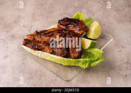 Teller mit heißen Schweinefleisch Rippchen auf dem Grill mit vorbereitet BBQ-Sauce auf einem Bett mit frischem Salat Stockfoto