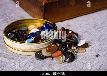 Schaltflächen auf dem Tisch in der Schneiderwerkstatt. Zubehör für die Schneiderei erforderlich. Dunkler Hintergrund. Stockfoto