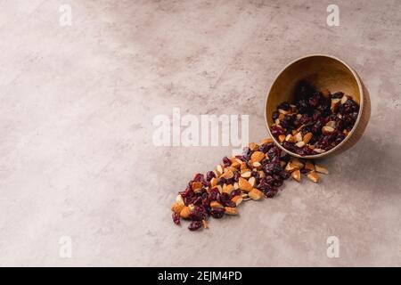 Blick auf eine Schale mit Mandeln und Heidelbeeren, fallen sie aus der Schale auf den Tisch eine sehr künstlerische Ansicht mit Platz für Text. Nüsse Sammlung in Holz Stockfoto