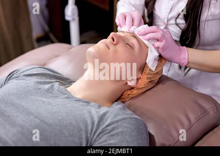 Calm Client Mann bekommen Gesichtsmassage Therapie in der ästhetischen Medizin Büro von professionellen Kosmetikerin. Medizin, Beauty-Konzept Stockfoto