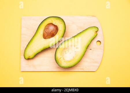 Hälften frischer Avocado auf Schneidebrett gelegt Stockfoto