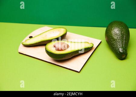 Köstliche frische Avocado-Früchte auf grüner Oberfläche angeordnet Stockfoto