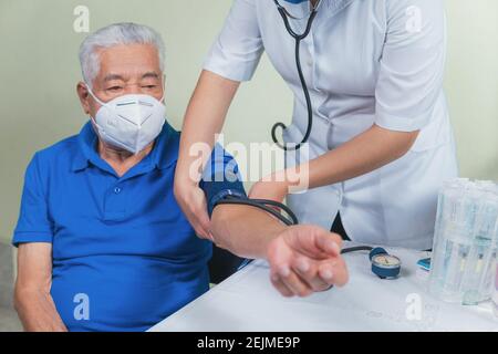 Zeigt, wie der Blutdruck bei einem älteren Mann gemessen wird Stockfoto