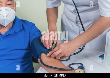 Zeigt, wie der Blutdruck bei einem älteren Mann gemessen wird Stockfoto