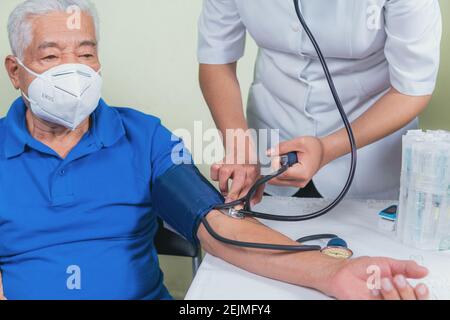 Zeigt, wie der Blutdruck bei einem älteren Mann gemessen wird Stockfoto