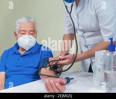 Zeigt, wie der Blutdruck bei einem älteren Mann gemessen wird Stockfoto