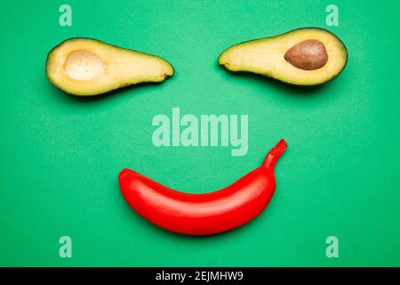 Rote Banane und halbierte Avocado auf grünem Hintergrund angeordnet Stockfoto