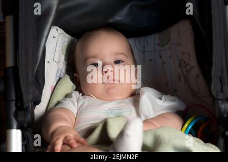 Säugling, Kindheit, Emotion Konzept - ziemlich süß lächelnd traurig schläfrig Gesicht von großen braunen Augen mollig Neugeborenen wach 7 Monate Baby Mädchen in weiß sieht aus Stockfoto