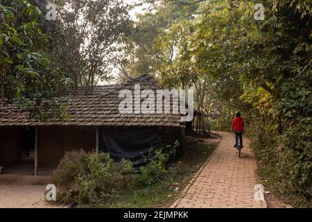 Malda, Westbengalen, Indien - Januar 2018: Eine schmale Gasse, die an einer strohgedeckten Dachhütte im Dorf Pandua in Malda vorbeiführt. Stockfoto