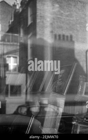 Großbritannien, West London, Notting Hill, 1973. Reflexionen in einem Schaufenster Verkauf von Antiquitäten auf Portobello Road. Stockfoto