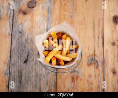 Rustikaler Eimer mit hausgemachten pommes auf Holztisch Stockfoto