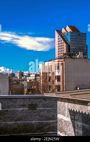 Ein klarer sonniger Wintertag mit Blick auf einen Neues Hochhausgebäude mit einer Glasfassade in Blau Himmel und schneebedeckte Berge des Elbrus liefen Stockfoto