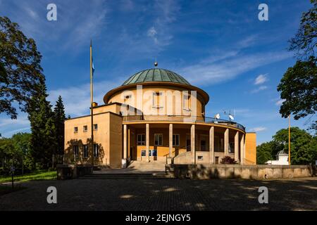 Prag, Tschechische Republik - Mai 23 2019: Ein rundes orangefarbenes Planetariumgebäude, umgeben von Bäumen, in einem Park namens Stromovka. Heller, sonniger Tag. Stockfoto