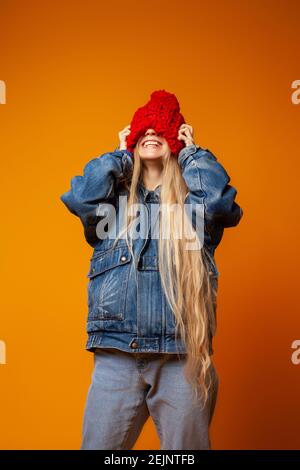 Hipster Frau in rot gestrickt Hut vor orangenen Hintergrund Stockfoto