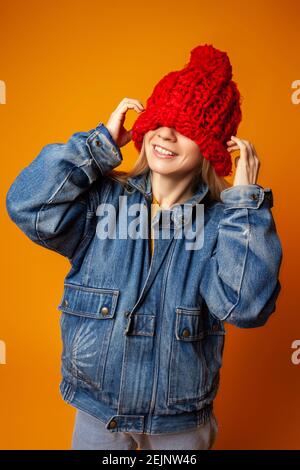 Hipster Frau in rot gestrickt Hut vor orangenen Hintergrund Stockfoto