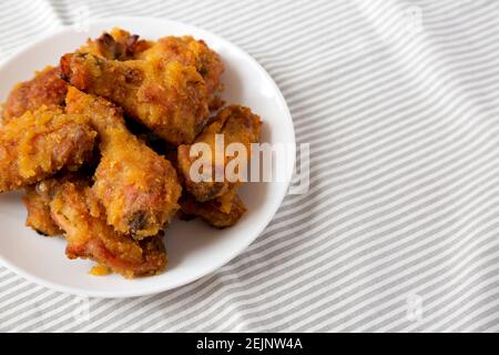 Hausgemachte würzige Mango Chicken Wings auf einem weißen Teller auf Tuch, Seitenansicht. Leerzeichen für Text. Stockfoto