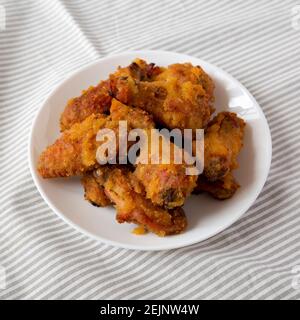 Hausgemachte würzige Mango Chicken Wings auf einem weißen Teller auf Tuch, Low-Angle-Ansicht. Stockfoto