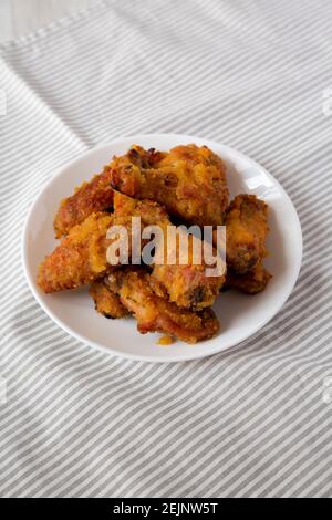 Hausgemachte würzige Mango Chicken Wings auf einem weißen Teller auf Tuch, Low-Angle-Ansicht. Stockfoto