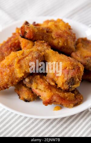 Hausgemachte würzige Mango Chicken Wings auf einem weißen Teller auf Tuch, Seitenansicht. Nahaufnahme. Stockfoto