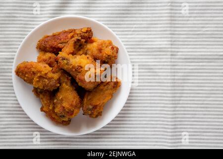 Hausgemachte würzige Mango Chicken Wings auf einem weißen Teller auf Tuch, Draufsicht. Flachlage, über Kopf, von oben. Speicherplatz kopieren. Stockfoto