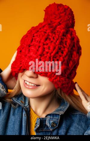 Hipster Frau in rot gestrickt Hut vor orangenen Hintergrund Stockfoto