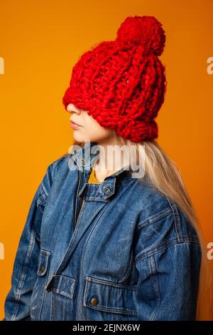 Hipster Frau in rot gestrickt Hut vor orangenen Hintergrund Stockfoto