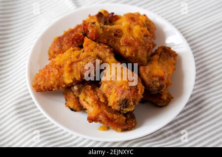 Hausgemachte würzige Mango Chicken Wings auf einem weißen Teller auf Tuch, Seitenansicht. Nahaufnahme. Stockfoto