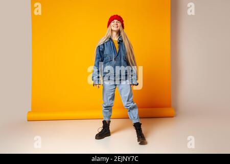 Fröhliche trendige Frau in Denim-Outfit und Hut mit Spaß Im Studio Stockfoto