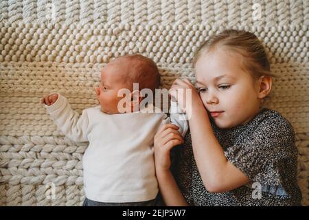 Liebenswert weiße Schwester hält neugeborenen Babys Hand zu Hause zeigen Liebe Stockfoto