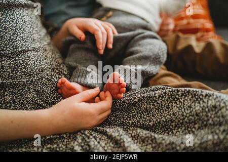Nahaufnahme eines älteren Kindes, das die Füße des Neugeborenen hält Zu Hause Stockfoto