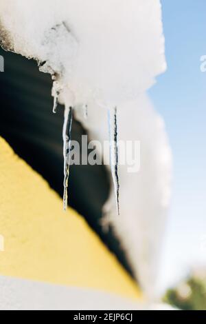 Scharfe Eiszapfen, die vom Dach herabhängen. Eisstalaktiten Stockfoto