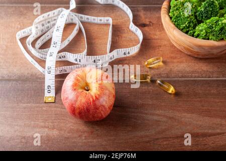 Eine Fitness, immer in Form, Ernährung, gesundes Leben Konzept Bild mit einer Nahaufnahme oben Ansicht von einem Maßband, Nahrungsergänzungsmittel Pillen, frischen Brokkoli Stockfoto