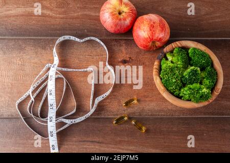 Eine Fitness, immer in Form, Ernährung, gesundes Leben Konzept Bild mit einer Nahaufnahme oben Ansicht von einem Maßband, Nahrungsergänzungsmittel Pillen, frischen Brokkoli Stockfoto