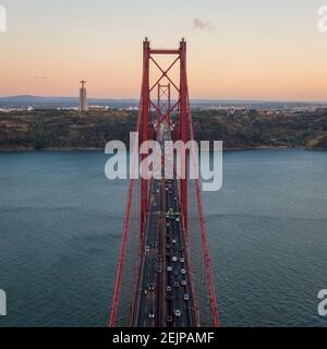 Luftaufnahme des Verkehrs auf der 25 de Abril Brücke über den Tejo bei Sonnenuntergang in Lissabon, Portugal. Stockfoto