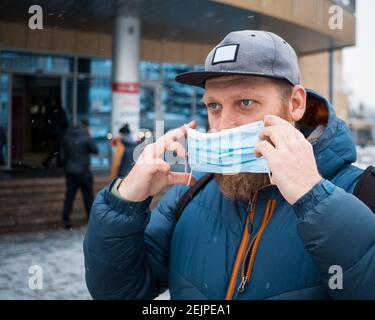 Mann, der an einem Wintertag Gesichtsmaske aufsetzt Stockfoto