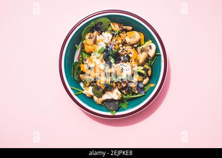 Hähnchen-Satay-Salat in vollem Sonnenlicht auf pastellrosa Hintergrund. Stockfoto