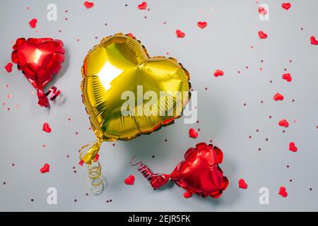 Rote und gelbe Luftballons aus herzförmiger Folie auf festlichem Hintergrund. Liebeskonzept. Feiertagsfeier. Valentinstag oder Hochzeit Stockfoto