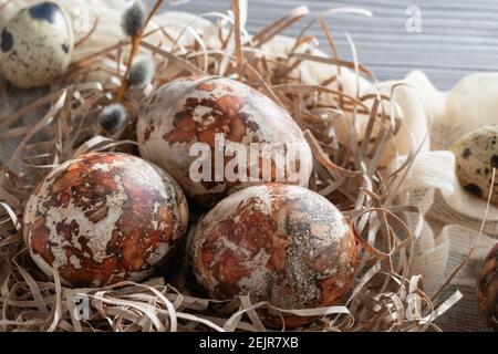 Ostern Zusammensetzung - mehrere Marmoreier mit natürlichen Farbstoffen in einem Papiernest auf dem Tisch gemalt. Stockfoto