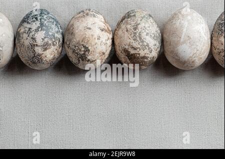 Ostern Komposition - mehrere mit natürlichen Farbstoffen mit Marmor-Effekt auf einem Leinentischtuch in einer Reihe gemalt. Stockfoto